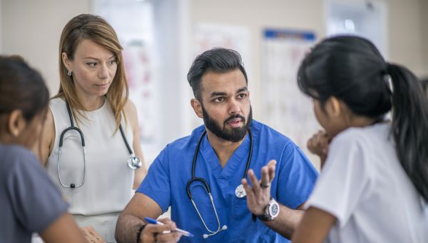 a multi-ethnic team of healthcare professionals, including doctors and nurses, gathers around a conference table to discuss the care plan for a patient