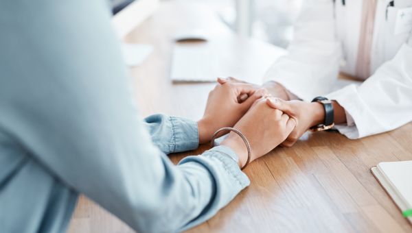 female healthcare provider holding hands with patient