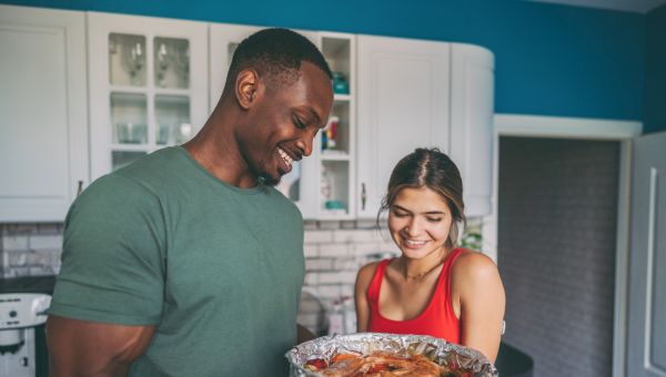 happy couple cooking salmon in kitchen