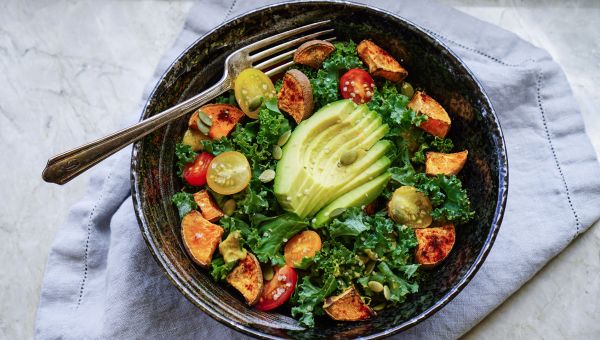 A kale salad with grape tomatoes and plenty of avocado.