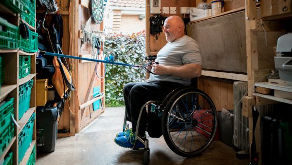 Older man in a wheelchair using resistance bands for a simple at-home workout.