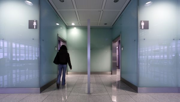 a woman walks into a public women's bathroom, adjacent to a men's bathroom with no one walking in