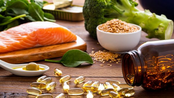 A table filled with salmon, broccoli, oils, and supplements.