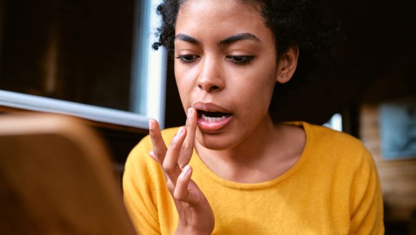 woman applying lip balm in mirror to prevent dry lips