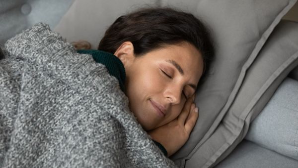 man snoring, headache, woman plugging ears in bed