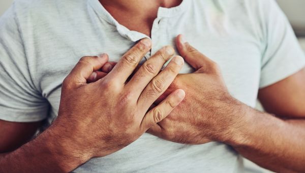 hands holding their chest during a heart attack