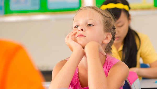 Girl with overlooked ADHD sits in classroom looking despondent 