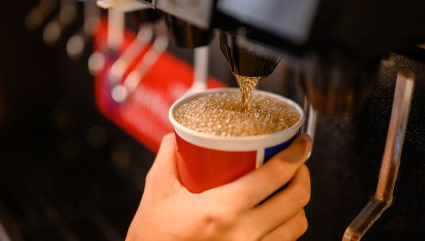 view of a hand dispensing soda from a fountain into a paper cup