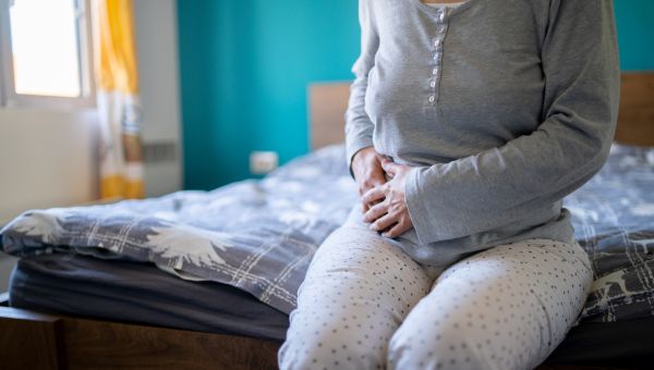 woman sitting on her bed holding her side from appendix pain
