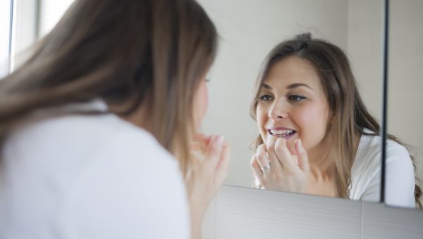 woman looking in the bathroom mirror at her teeth 