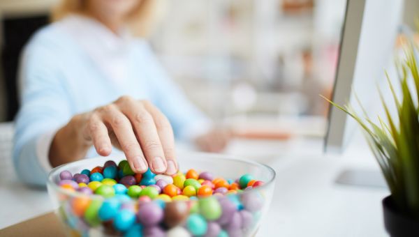 woman reaching for sugar-free candies at her desk