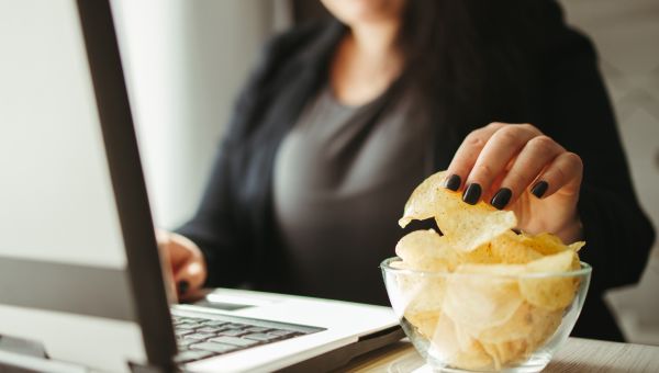 woman reaching for potato chips at her desk