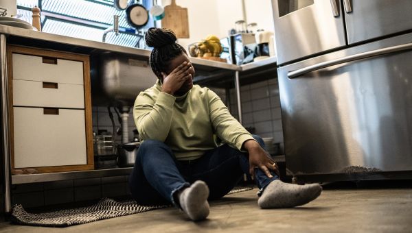 stressed woman sitting on kitchen floor