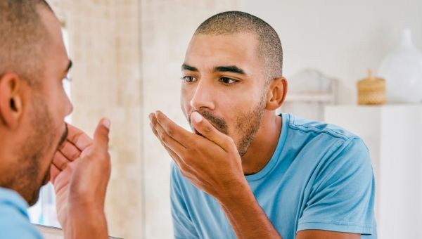 man check his bad breath in the bathroom mirror