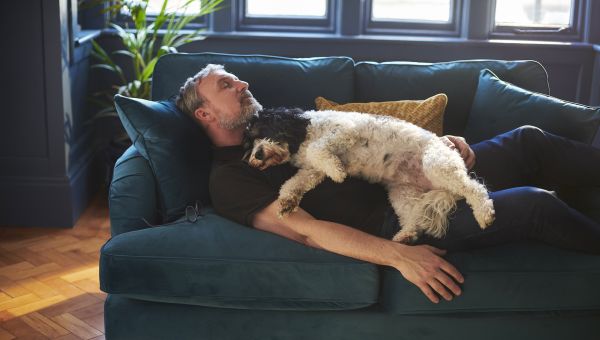 man taking a nap with dog on couch