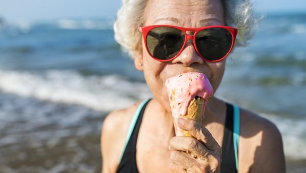 senior woman eating icecream on the beach