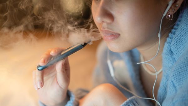 woman smoking electronic cigarette in bed