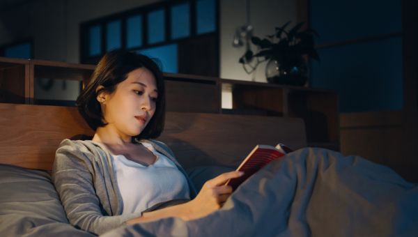 woman reading book in bed