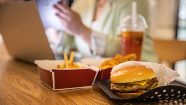 woman at work with fast food next to her on the desk