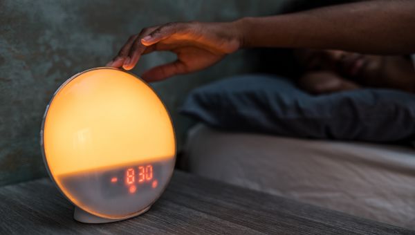 woman reaching for her alarm clock