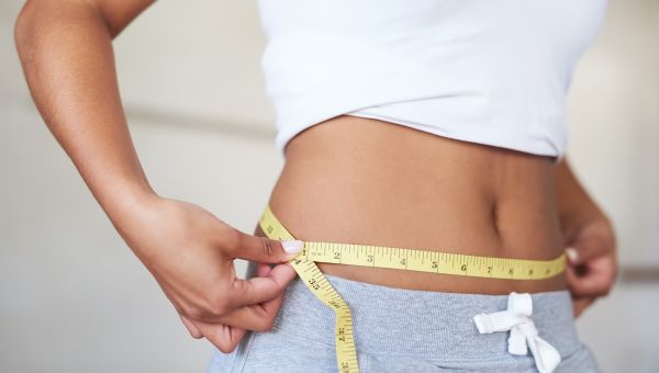 woman holding measuring tape around stomach