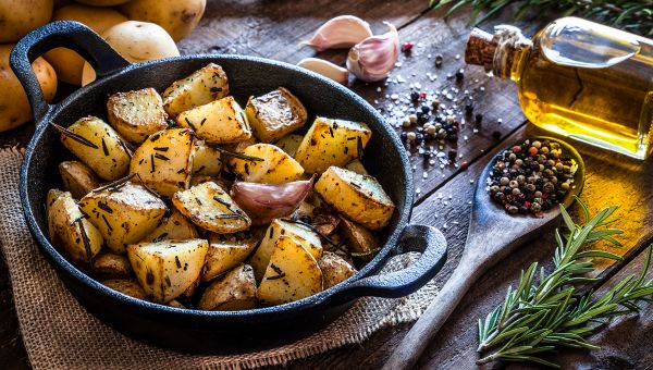 A cast-iron filled with roasted potatoes and rosemary