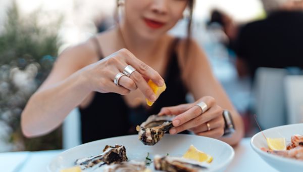 Someone sprinkling lemon juice on oysters