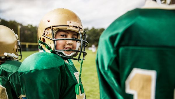 tween boy in football helmet on field