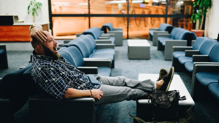 Tired man with beard yawning in airport