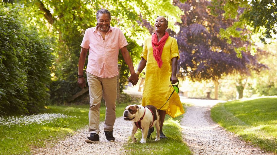 happy couple walking in a park with a dog