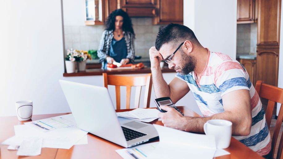 Man stressing out over finances at kitchen table