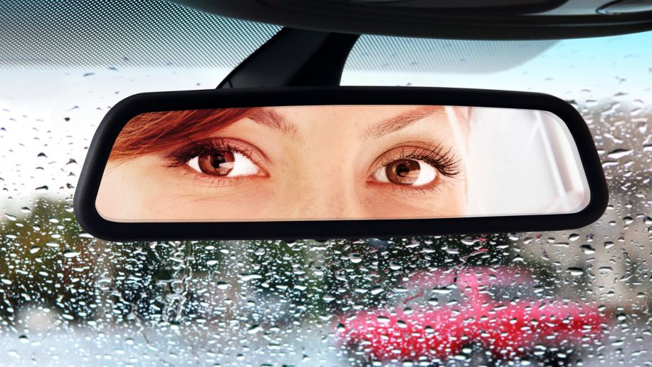 View of a woman's eyes as she looks in a rearview mirror.