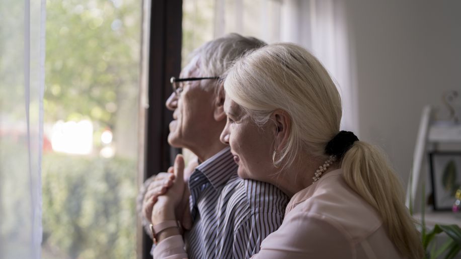 senior couple looking pensively out window