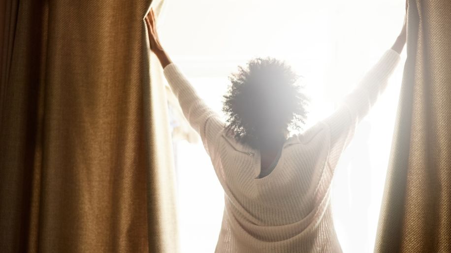 opening curtains to let light in