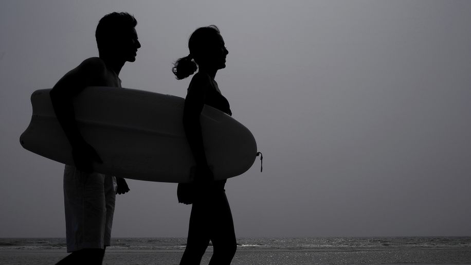 Silhouette of couple getting ready to go surfing.