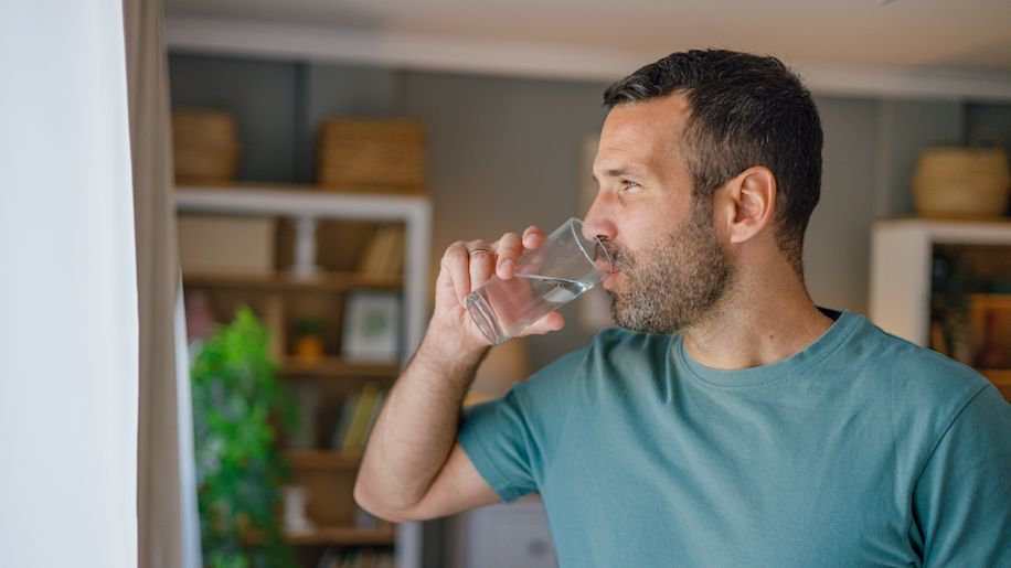 young man drinking water at home