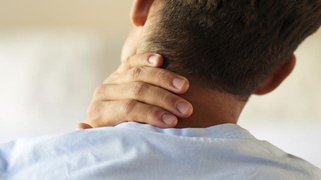 man rubbing back of neck