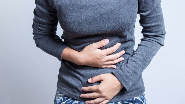 A woman clutches her stomach and wonders what causes constipation and if there is medication that causes constipation. 
