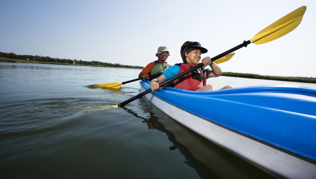 Low angle of African American middle-aged man and woman paddling kayak.