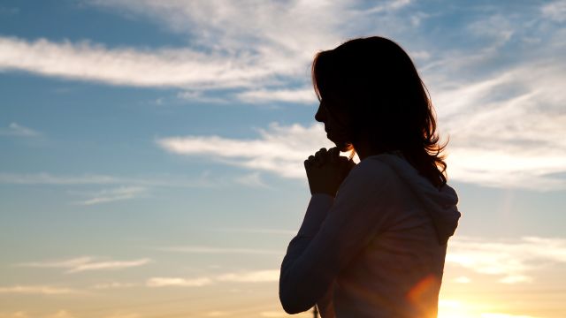 silhouette of a woman with thoughtful or pensive posture with evening sky background