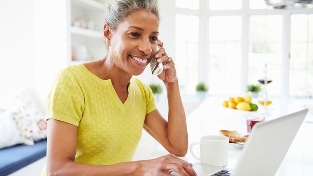 woman using laptop and-talking-on-phone-at-home