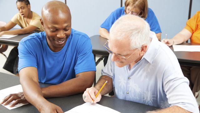 Older students in a classroom looking over their work.