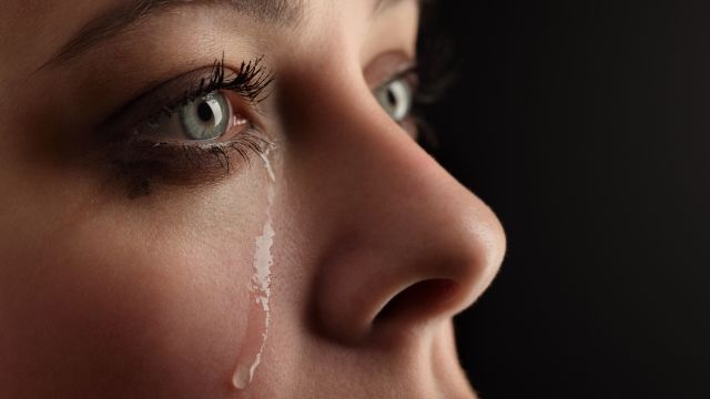 Woman with tears streaming down her cheek.