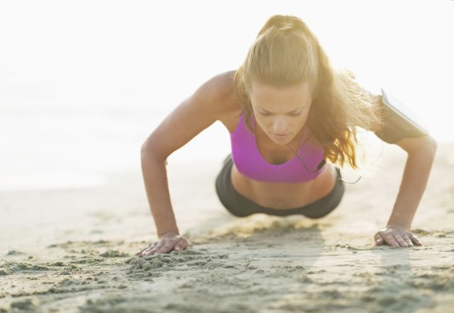 fitness young woman doing push ups on beach