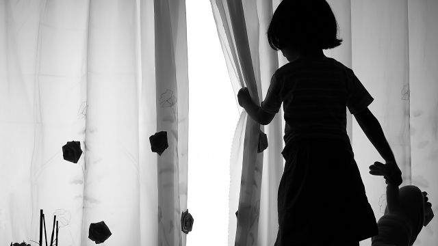 A child in silhouette looking out the window