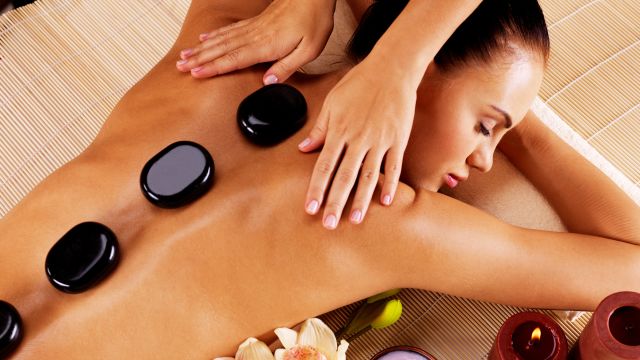 A woman relaxes with hot stones on her back as she enjoys massage therapy for fibromyalgia, an alternative therapy for pain. 