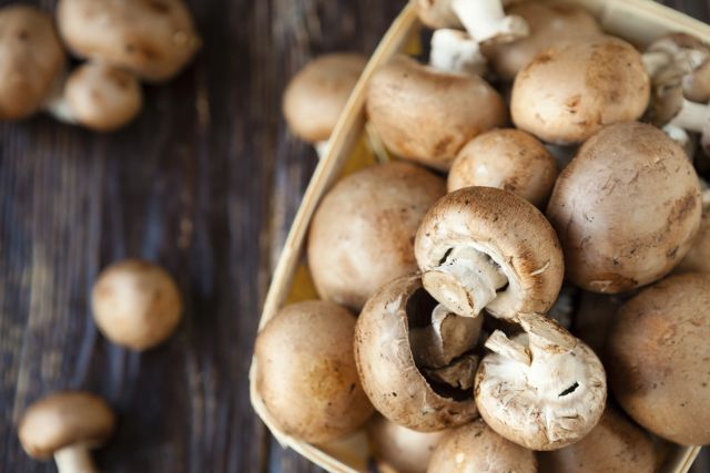 Mushrooms in a basket against a dark board table background 