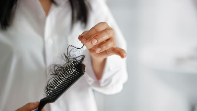 woman picking hair out of hairbrush