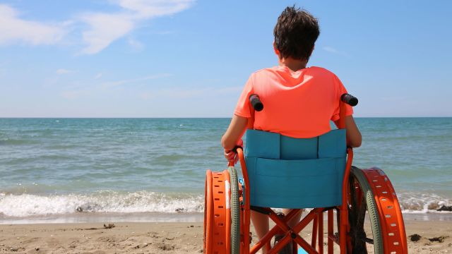 child in wheelchair on beach