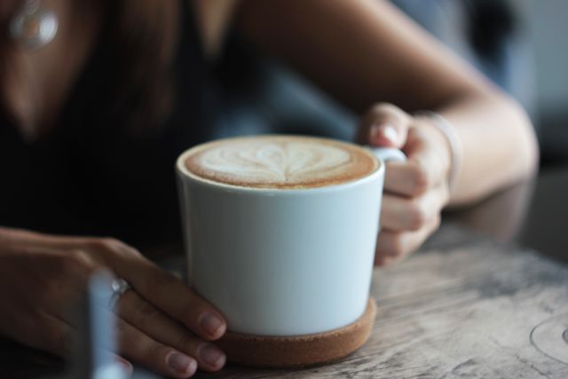 Woman's hand holding latte with foam art